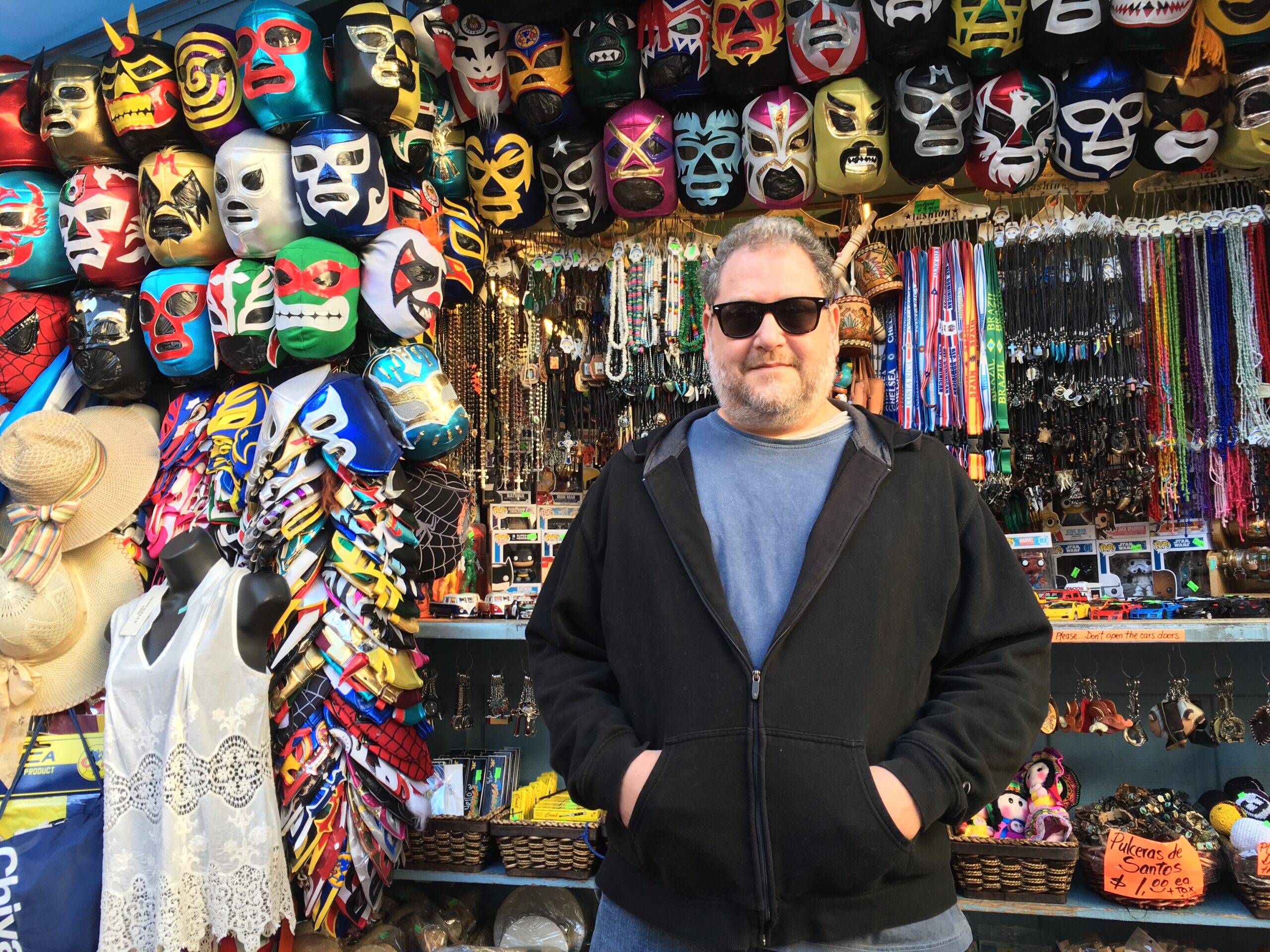 Author standing in front of wrestling masks by Jessica Handler
